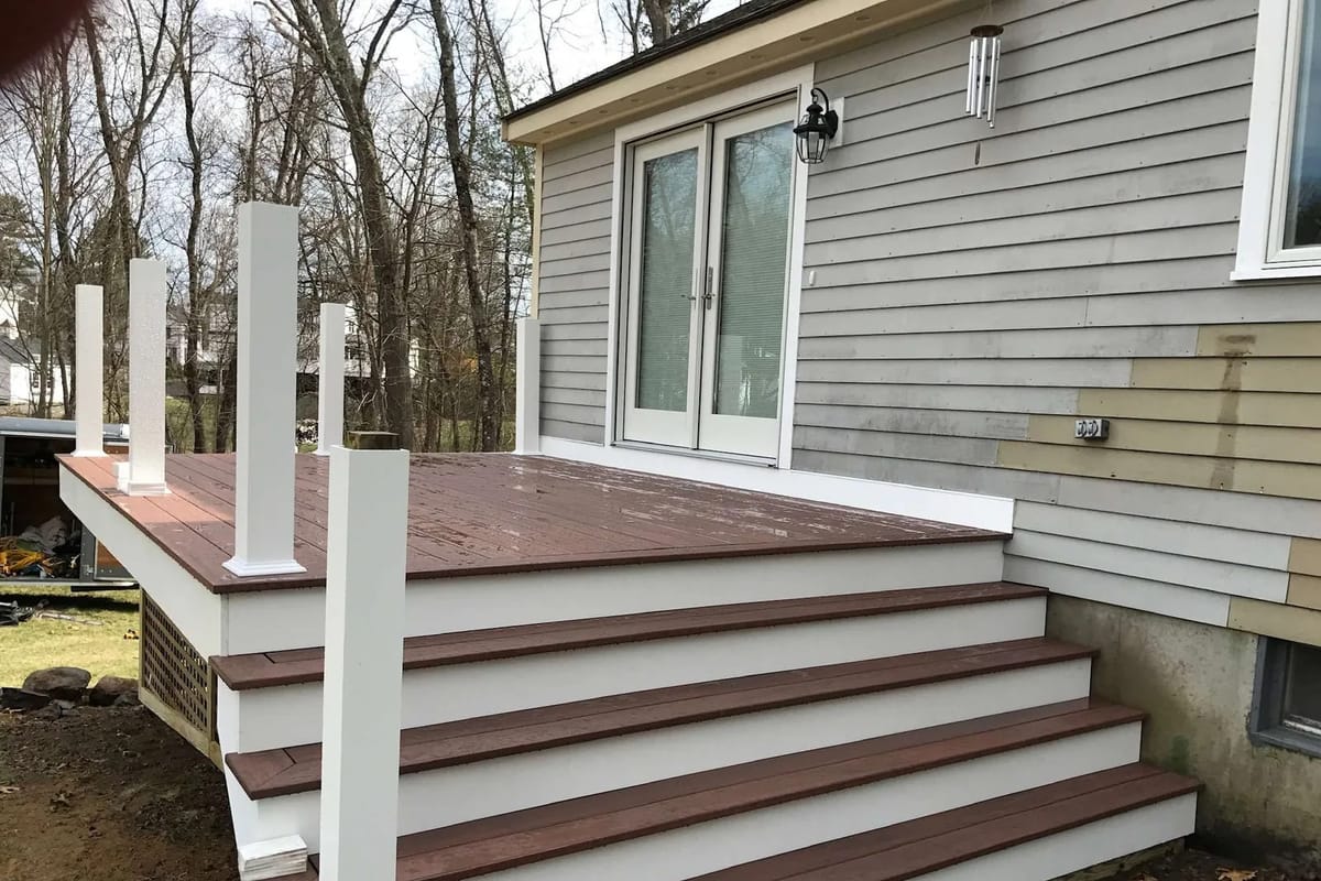 Deck build: decking boards, wide stairs and white posts installed