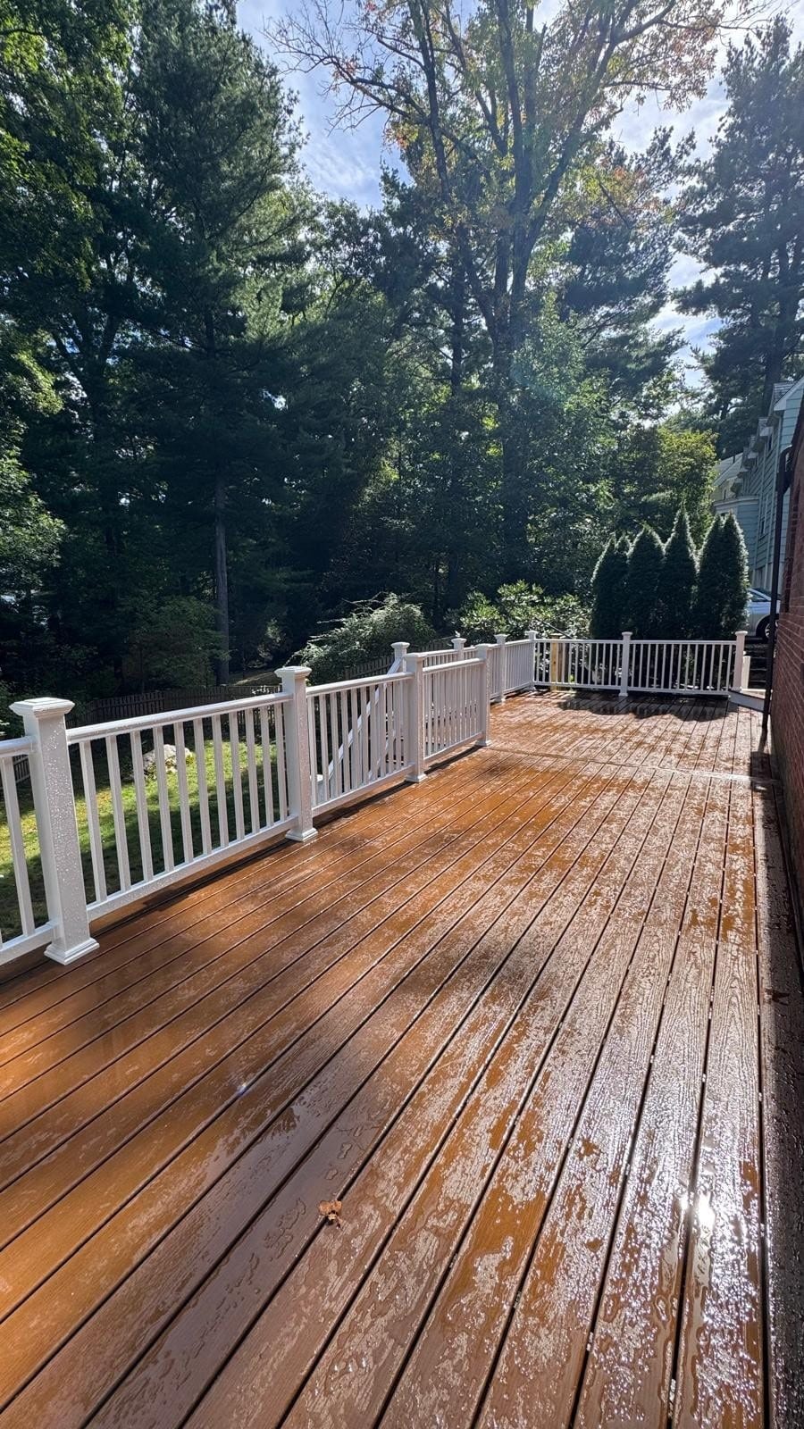 Deck renovation in Newton, MA: beautifully renovated composite deck featuring warm brown decking, white PVC railings, and a spacious outdoor living area