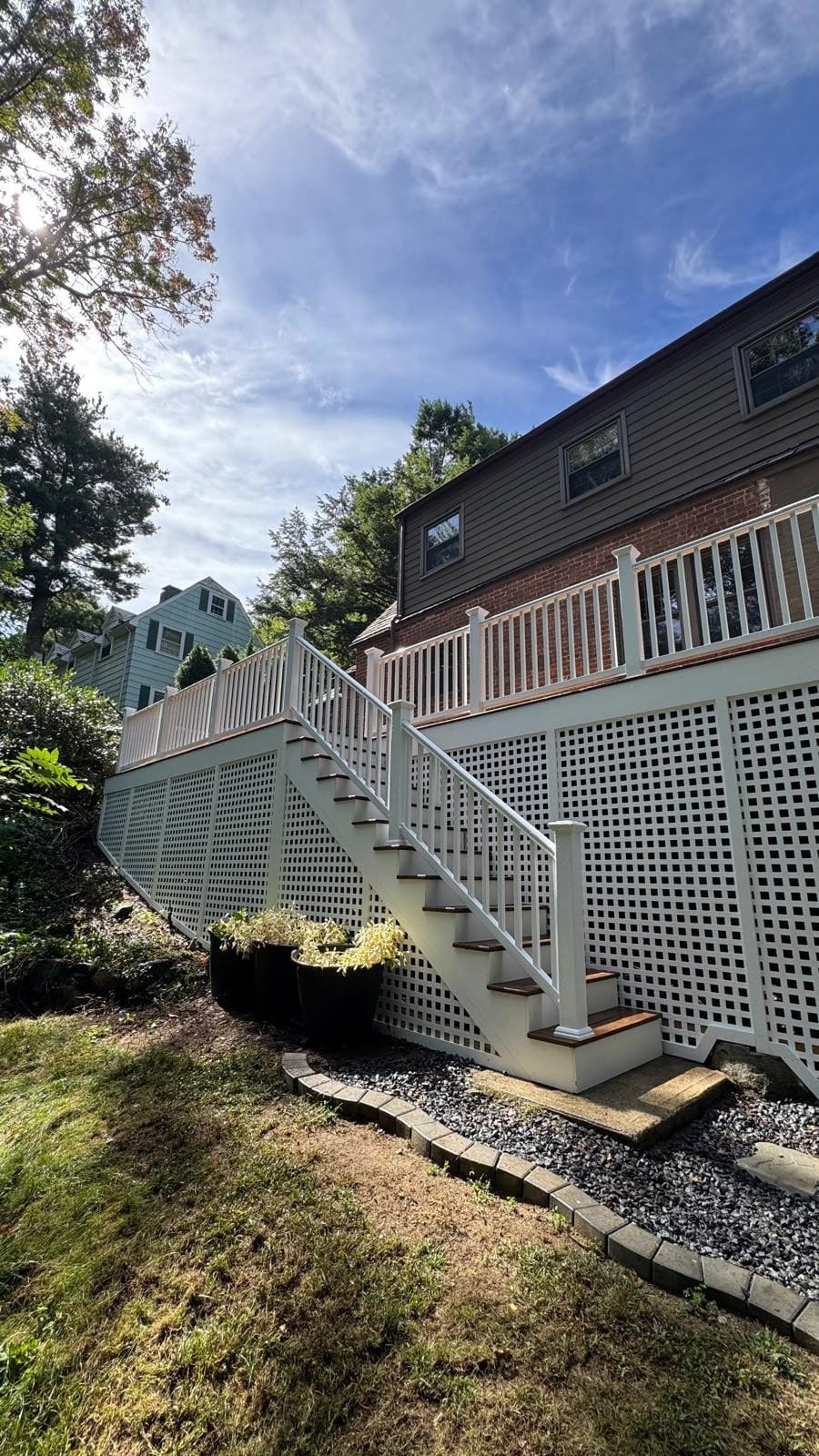 Deck renovation in Newton, MA: composite decking, white lattice skirting, matching stairs, and elegant PVC railings
