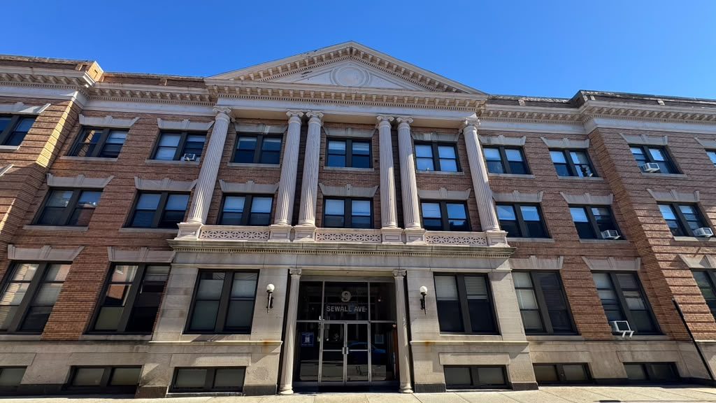 Three-story brick apartment building with stone columns and a central entrance