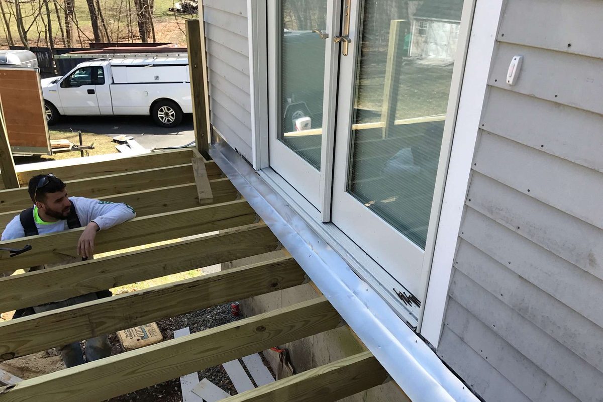 Crew member installing joists along the house next to the French doors