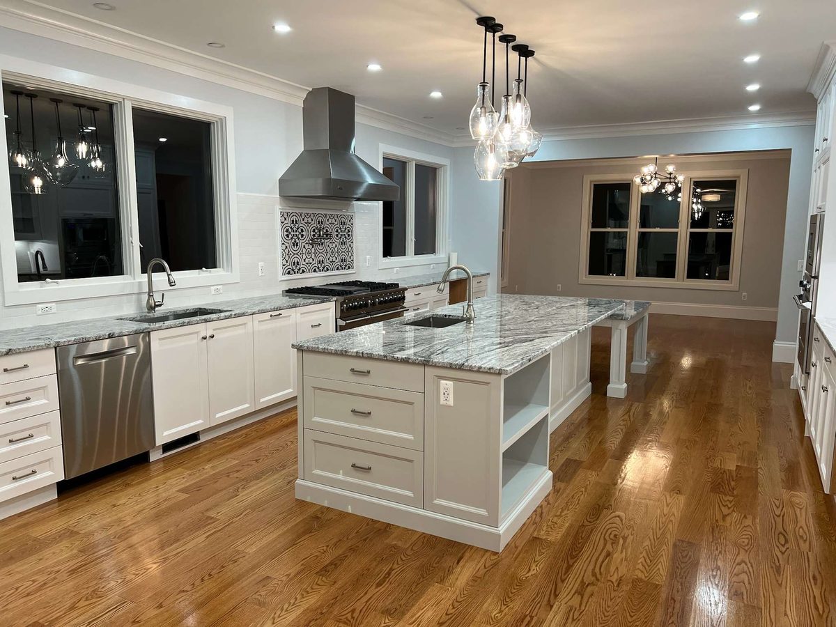 Kitchen island with drawer storage and open shelving, glass pendant lights and a patterned tile backsplash behind the range