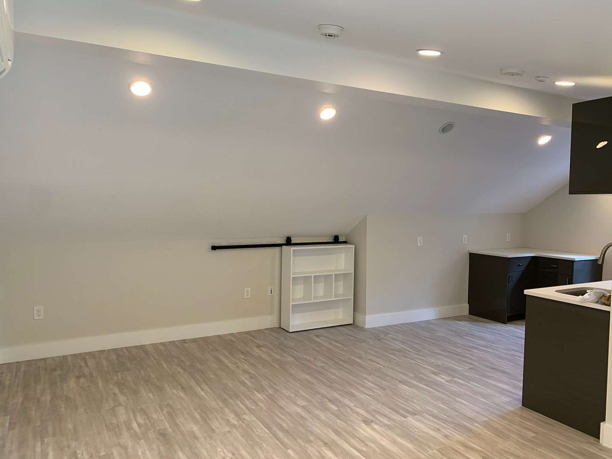 Finished attic apartment with sloped ceilings, recessed lighting and wood-look flooring