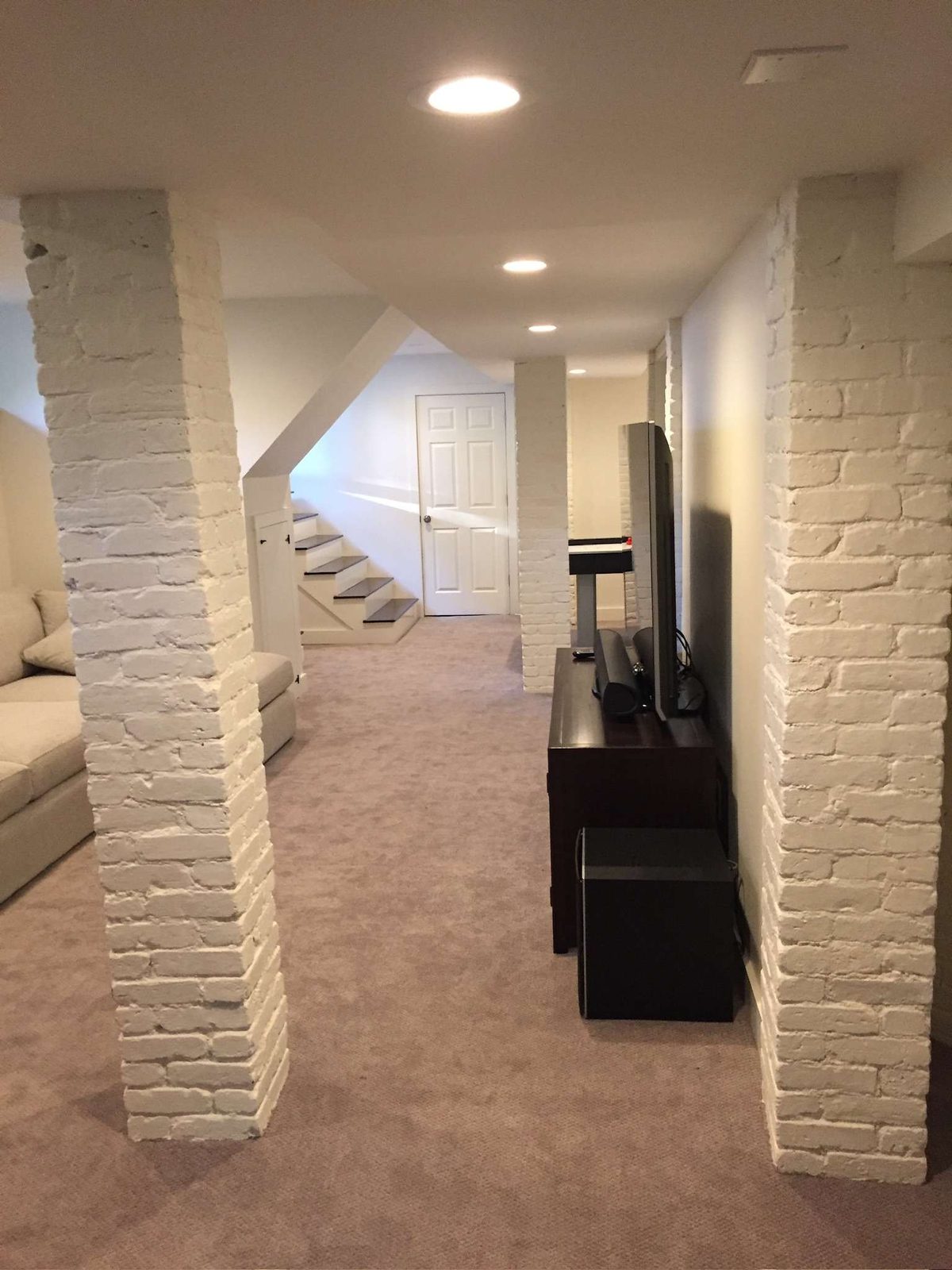Finished basement with painted brick columns, recessed lighting and carpet