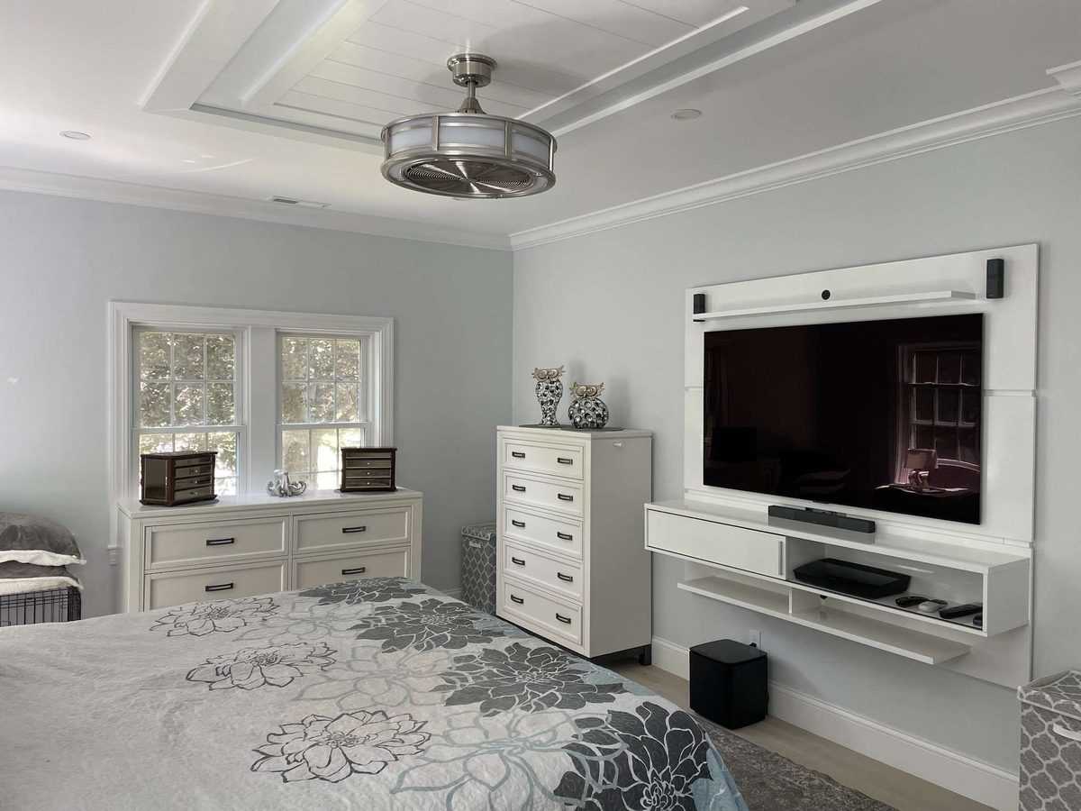 Bedroom with a tray ceiling and a wall-mounted media panel with floating shelves